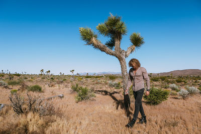 Man standing by tree on field against sky