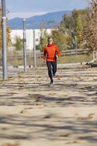 Senior man running on road during autumn