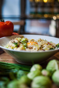 Close-up of food served in bowl by vegetables on table