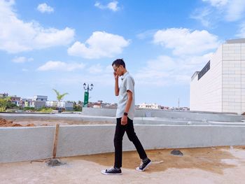 Full length of young man standing against sky in city