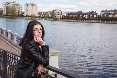 Young woman standing by railing in river