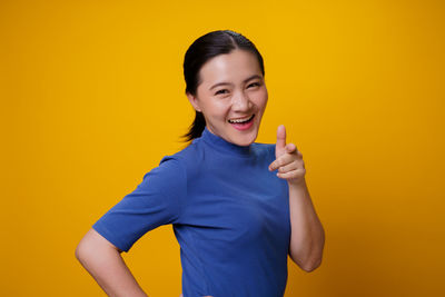 Portrait of smiling man standing against yellow background