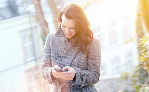 Close-up of woman using mobile phone while standing on footpath