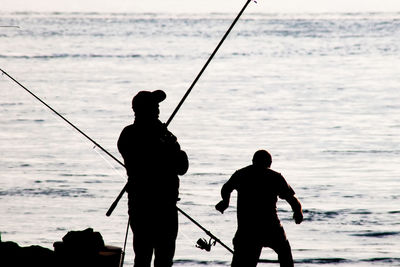 Silhouette man fishing on beach