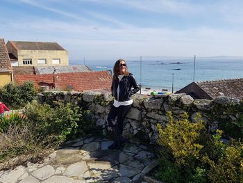 Woman standing by retaining wall against sea