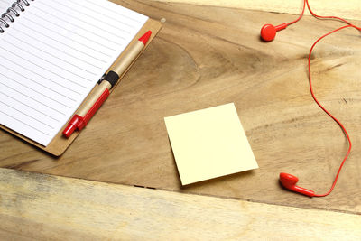 High angle view of book with mobile phone and headphones on wooden table