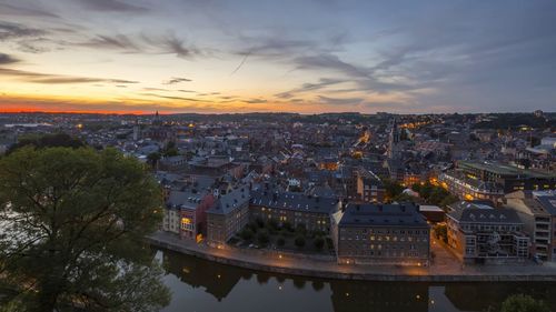 High angle view of illuminated buildings by river against sky