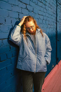 Young woman standing against wall