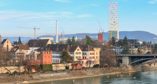 Bridge over river by buildings in city against sky