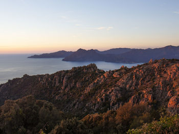 Scenic view of sea and mountains against sky during sunset