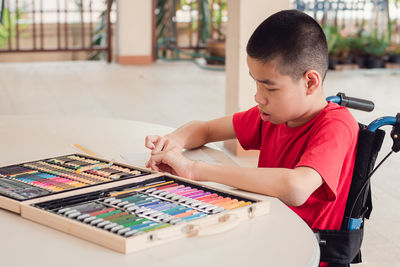 Rear view of boy sitting on table