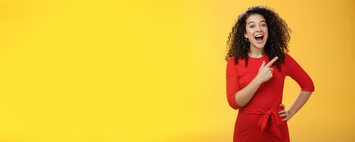 Young woman standing against yellow background