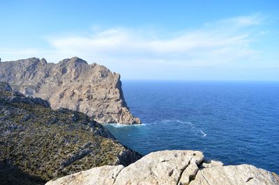 Scenic view of rocks by sea against sky