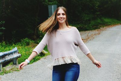 Portrait of smiling young woman standing against trees