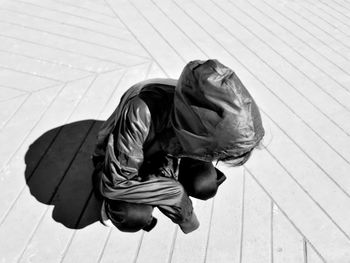 High angle view of woman crouching on footpath