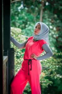 Portrait of young woman standing against trees