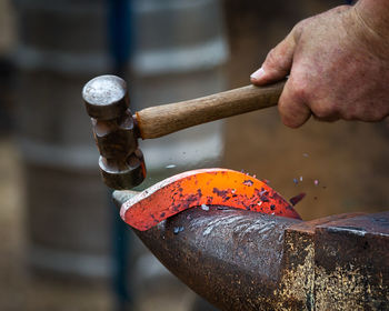 Cropped image of blacksmith shaping horseshoe in industry