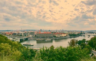 Scenic view of river by cityscape against sky