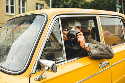 Reflection of man photographing through car window