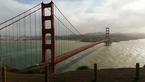 Suspension bridge against cloudy sky