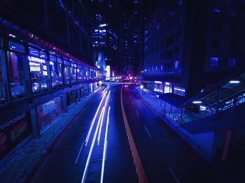 Illuminated road amidst buildings in city at night