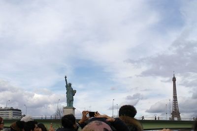 Group of people in front of building against cloudy sky