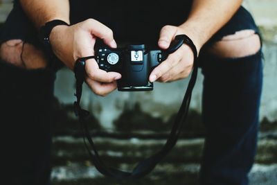 Midsection of man photographing with digital camera