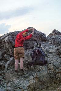 Female hiker exercising on rocks against sky