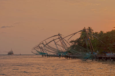 Fishing net on beach against sky during sunset
