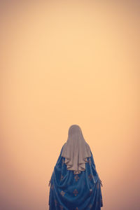 Rear view of people standing against orange sky