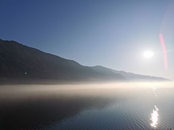 Scenic view of lake and mountains against bright sky