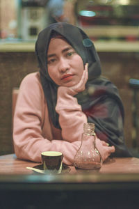 Portrait of young woman sitting on table at cafe