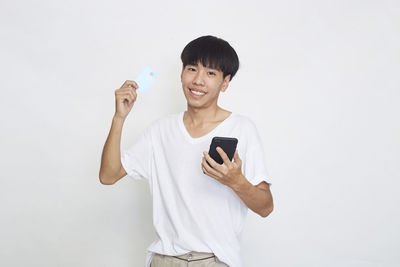 Young man using smart phone against white background