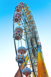 Low angle view of ferris wheel against clear blue sky