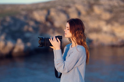 Side view of woman standing against sea