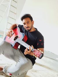 Portrait of man playing guitar at home