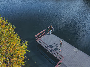 Aerial view of young woman standing alone at edge of coastal jetty