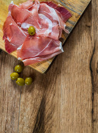 Serrano ham with olives on wood background with copy space