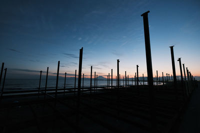 Silhouette of wooden post in sea against sky