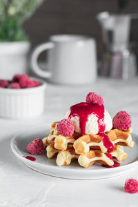 Freshly baked waffles with raspberry syrup and ice cream on a plate