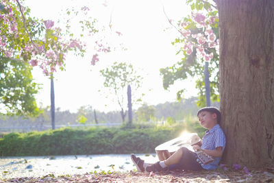 Boy playing guitar while sitting in park