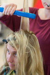 Close-up of hair dresser shaping customer hair at salon