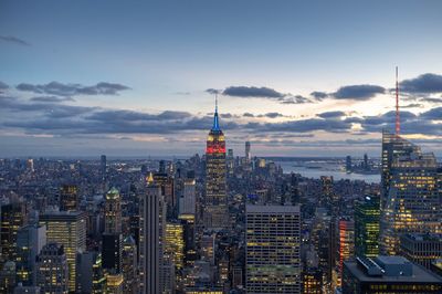 Aerial view of buildings in city against cloudy sky