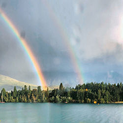 Scenic view of rainbow over lake against sky