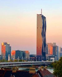 Modern buildings in city against sky during sunset