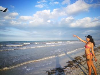 Sensuous woman wearing bikini pointing at beach