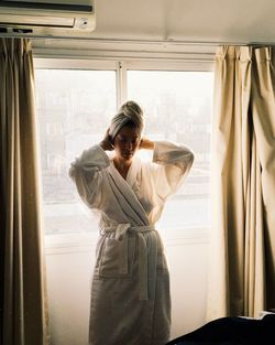 Woman standing by window at home