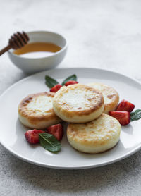 Cottage cheese pancakes, ricotta fritters on ceramic plate with fresh strawberry. 