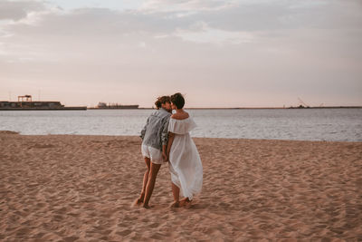 Two women walking on the beach and kissing.