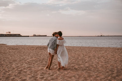 Rear view of woman on beach against sky during sunset